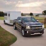 A black 2017 Chevy Silverado 1500 is shown towing a trailer after visiting a used truck dealer in Indianapolis.