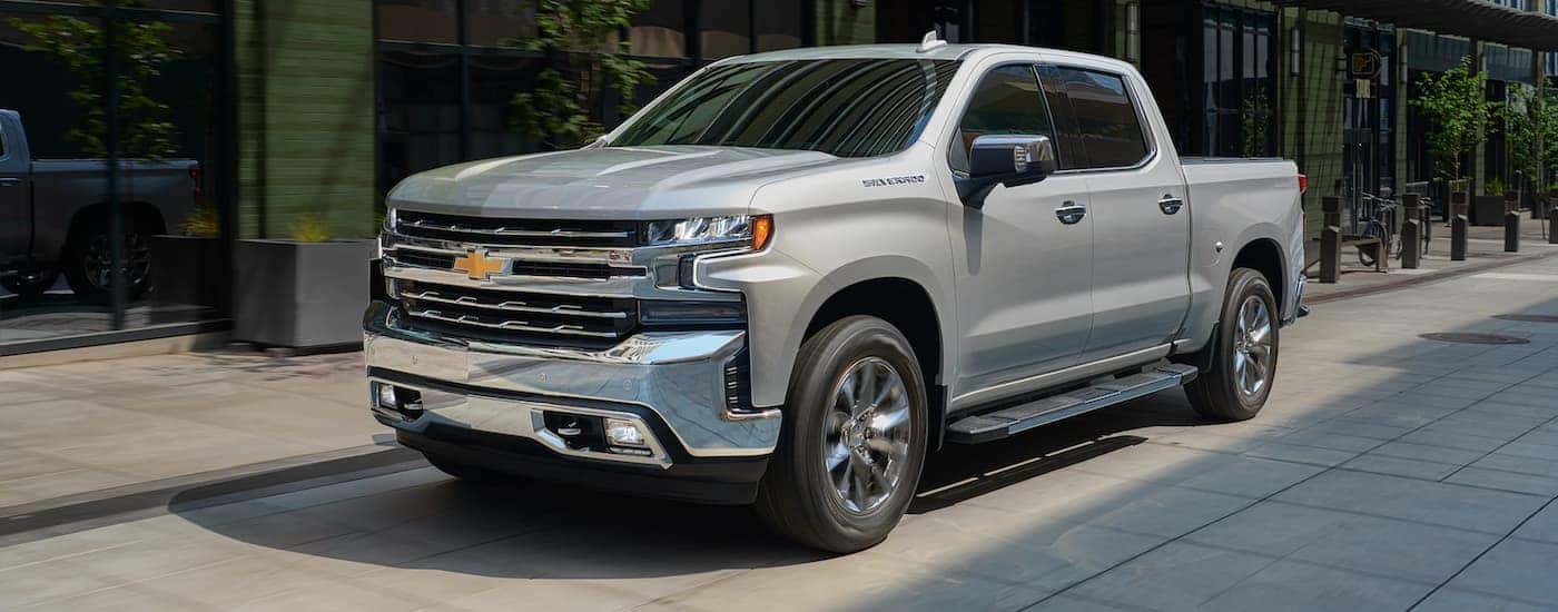 A silver 2021 Chevy Silverado is shown parked near a store.