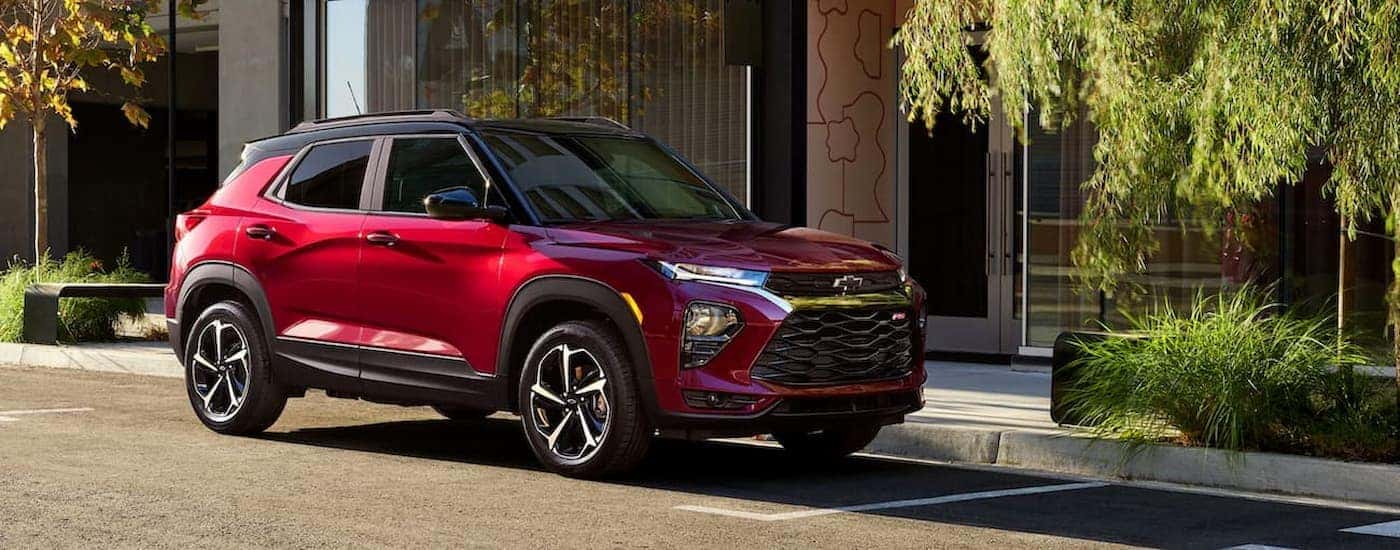 A red 202 Chevy Trailblazer RS is shown parked near a curb.