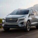 After competing in a 2024 Chevy Equinox vs 2024 Ford Escape comparison, a silver 2024 Chevy Equinox Premium, is shown driving on a highway.