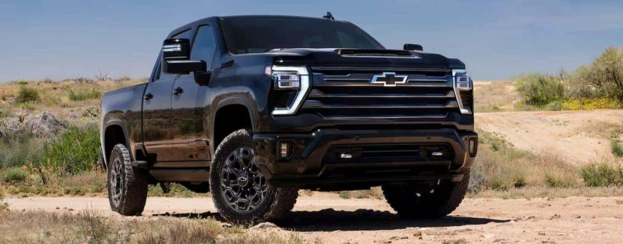 After competing in a 2024 Chevy Silverado 2500 HD vs 2024 Ram 2500 comparison, a black 2024 Chevy Silverado 2500 HD Midnight Edition, is shown parked off-road.