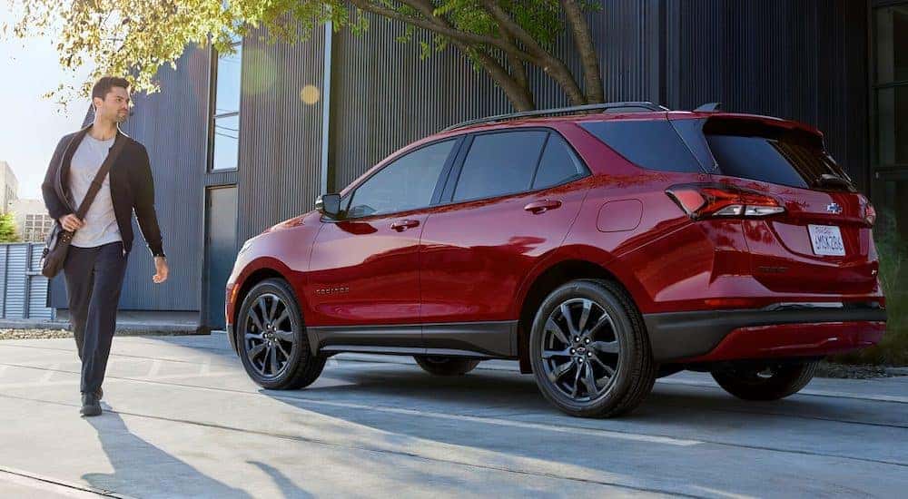 A red 2024 Chevy Equinox RS is shown parked near a curb.