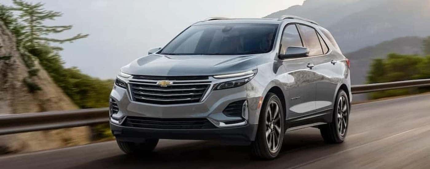 A silver 2024 Chevy Equinox is shown driving on a highway.