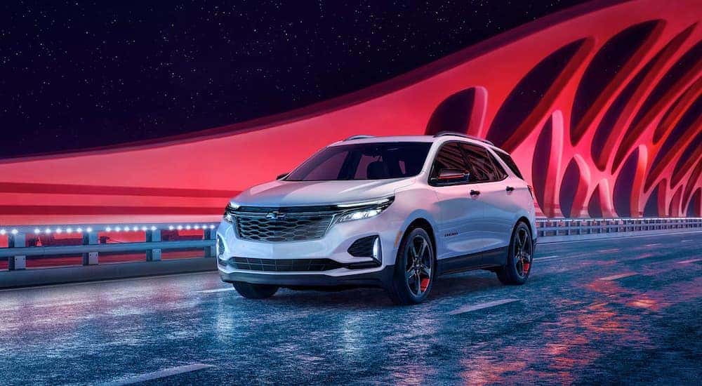 A white 2024 Chevy Equinox driving over a dramatic modern bridge.