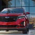 A red 2024 Chevy Equinox parked in front of a bank of windows.