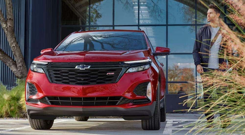 A red 2024 Chevy Equinox parked in front of a bank of windows.