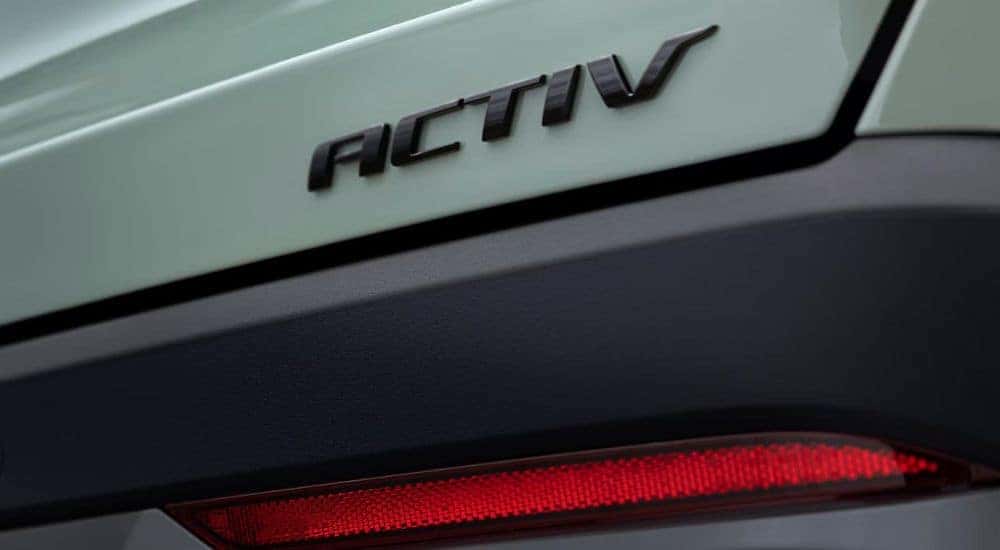 A close up shows the 'Activ' badge on the trunk of a green 2025 Chevy Equinox Activ.
