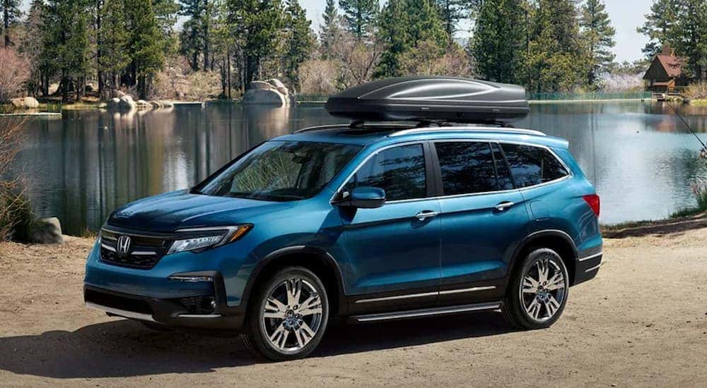 A blue 2020 Honda Pilot is parked near a lake.