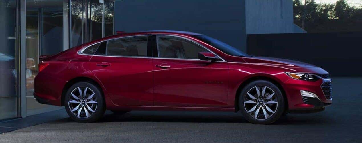 A red 2024 Chevy Malibu is shown parked near a house.