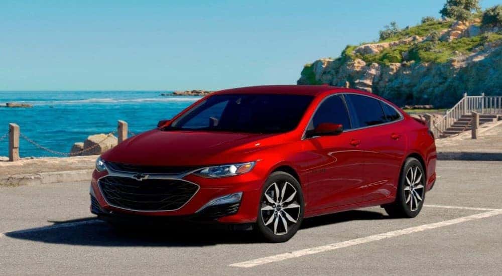 A red 2024 Chevy Malibu parked near the ocean.
