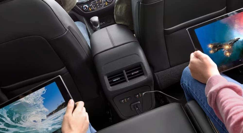 Two children are shown using tablets in the black interior of a 2024 Chevy Equinox.