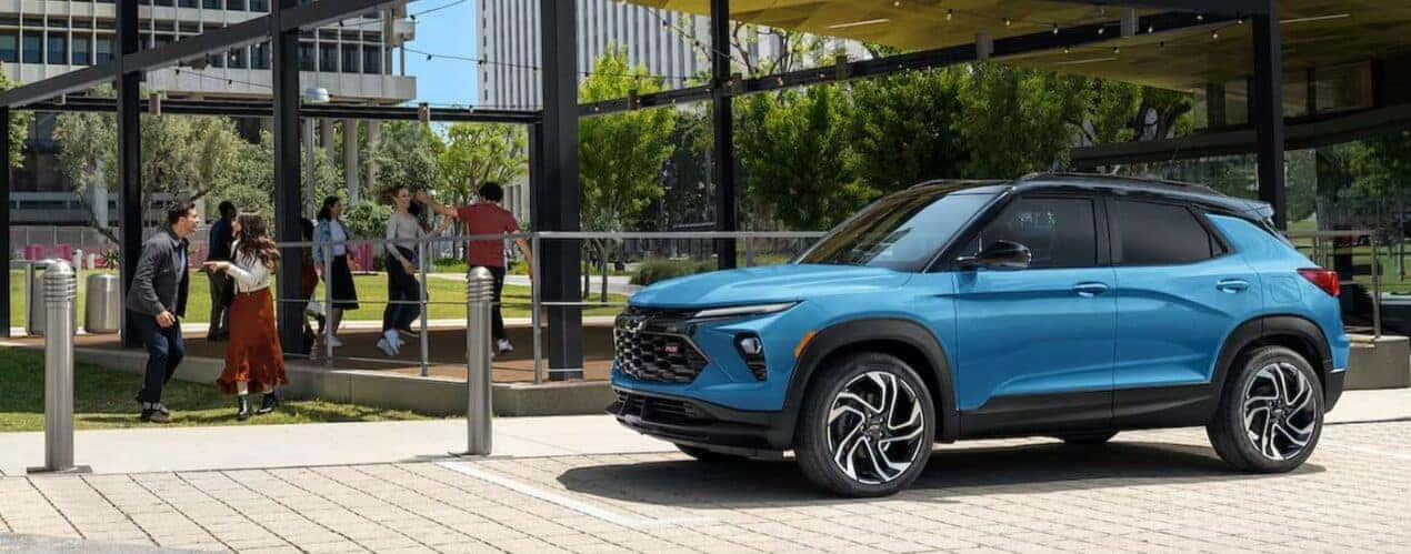 A blue 2024 Chevy Trailblazer RS is shown parked near people dancing.