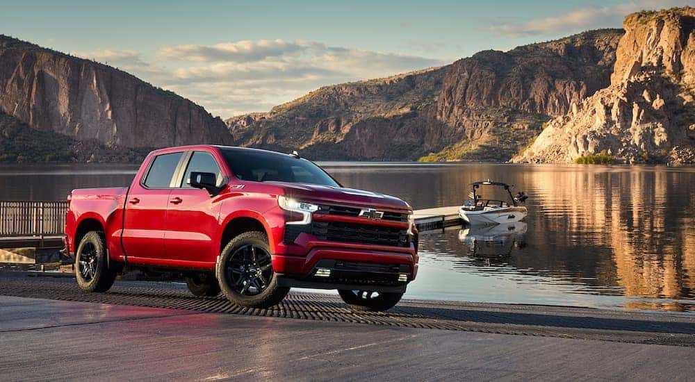 A red 2024 Chevy Silverado 1500 RST parked at a boat launch.