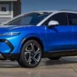 A blue 2024 Chevy Equinox EV is shown parked near an ocean.