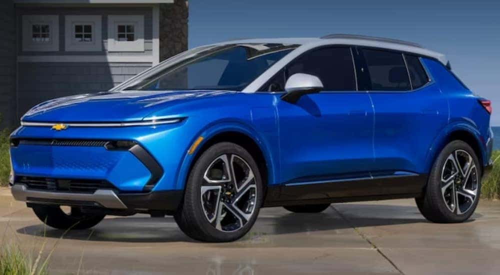 A blue 2024 Chevy Equinox EV is shown parked near an ocean.