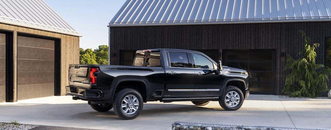 A black 2024 Chevy Silverado 2500 HD High Country is shown from the side.