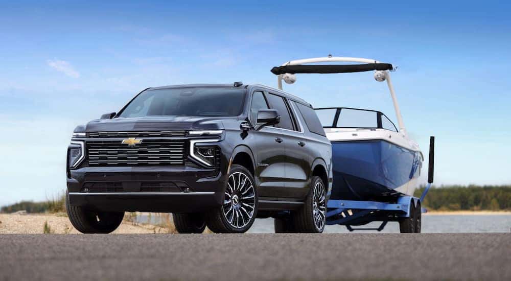 A black 2025 Chevy Suburban High Country is shown from the front at an angle after leaving a dealer that has SUVs for sale.
