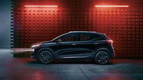 2023 Chevrolet Bolt EUV Premier Redline in Mosaic Black Metallic parked in front of a building with red lights over the vehicle.