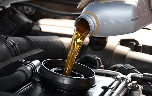 A service technician pouring new engine oil.