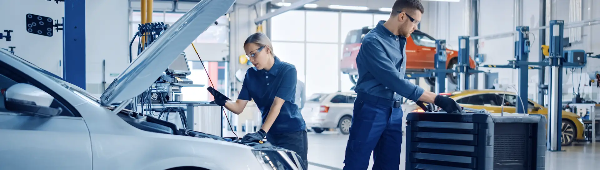 Two service technicians working on a car engine.