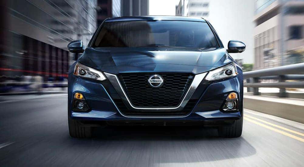A blue 2021 Nissan Altima is shown from the front on a city street.
