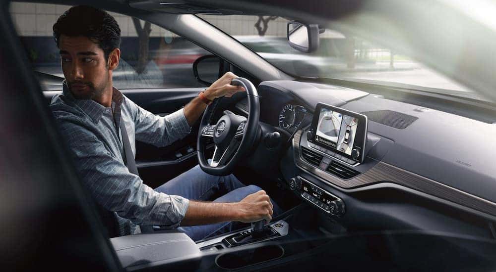 A man is reversing in a 2021 Nissan Altima, shown from the inside.