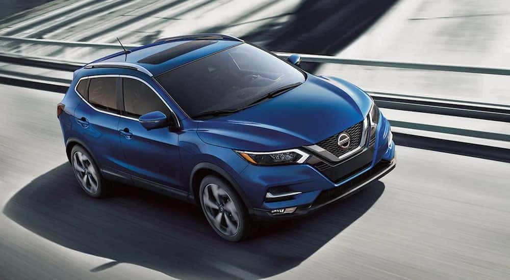 A blue 2021 Nissan Rogue is driving on a highway overpass after leaving a Louisville Nissan dealer.