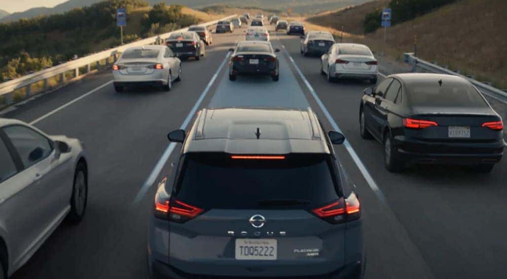 A grey 2021 Nissan Rogue Sport is on a busy highway with the lane highlighted blue.