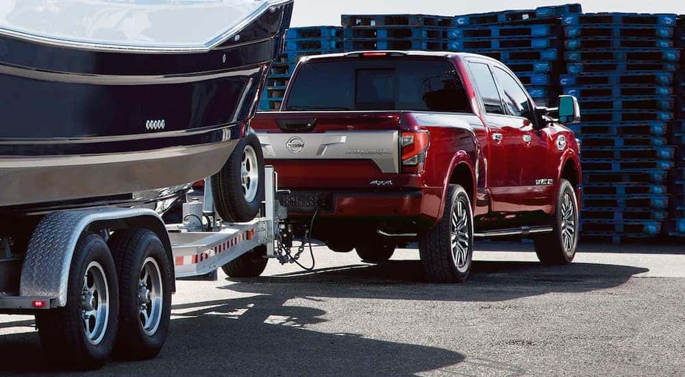 A red 2020 Nissan Titan is shown from behind while towing a boat after leaving a used Nissan dealership.