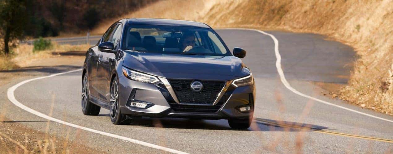 A gray 2021 Nissan Sentra is shown from the front driving on a winding road.