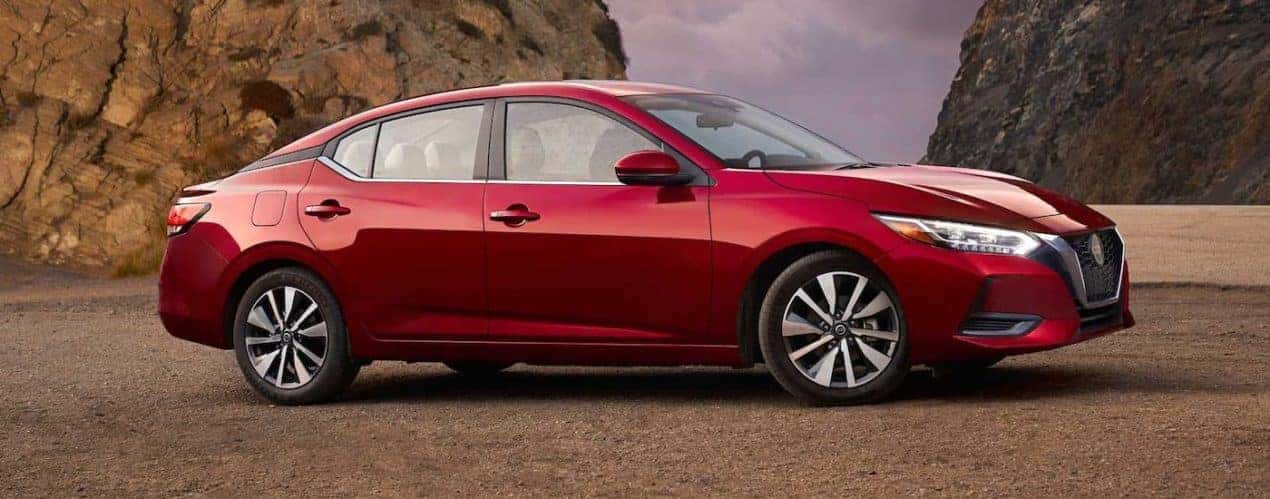 A red 2021 Nissan Sentra is shown from the side while parked in front of rocks.