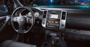 The interior of a 2020 Nissan Frontier shows the steering wheel and infotainment screen after leaving a Louisville used car lot.