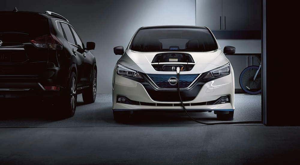 A white 2022 Nissan LEAF is shown charging in a garage.