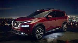 A red 2021 Nissan Rogue is shown from the side at night overlooking a city after leaving a Louisville Nissan Rogue dealer.