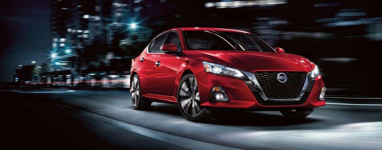 A red 2022 Nissan Altima is shown from the side driving on a city street.