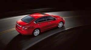 A red 2015 Nissan Altima is shown from a high angle driving on a street.