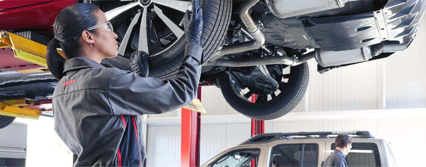 A Nissan technician is shown checking tire pressure during an inspection.