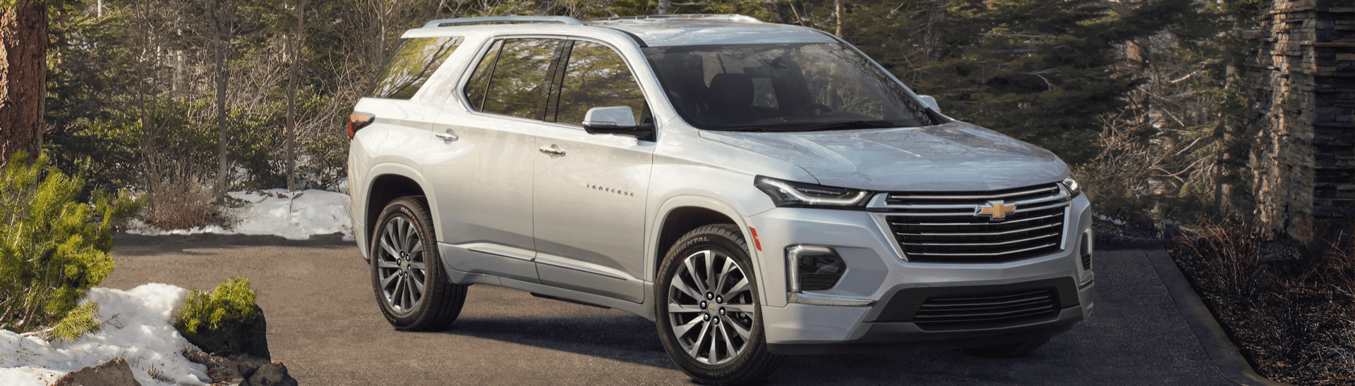 2022 Chevy Traverse Premier next to a cabin in the woods.