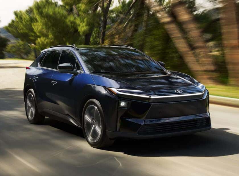 Toyota bZ4X Limited FWD in Elemental Silver Metallic with Black Roof accelerating down a tree-lined road.
