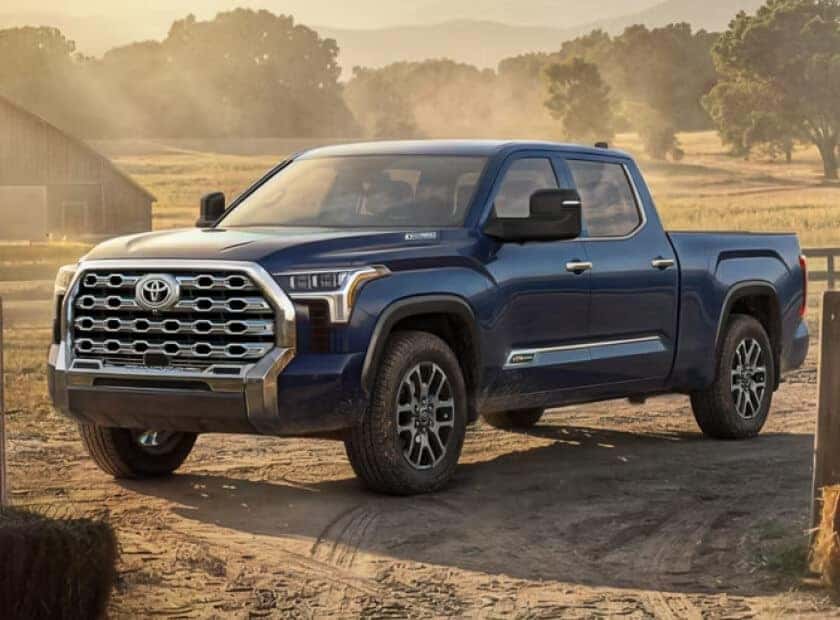 Toyota Tundra 1794 Edition CrewMax 4x4 in Blueprint showcasing its chrome grille parked inside a rustic barn opening.