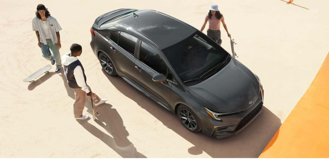 High-angle view of a Toyota Corolla Hybrid SE parked near skateboarders on an urban concrete plaza.