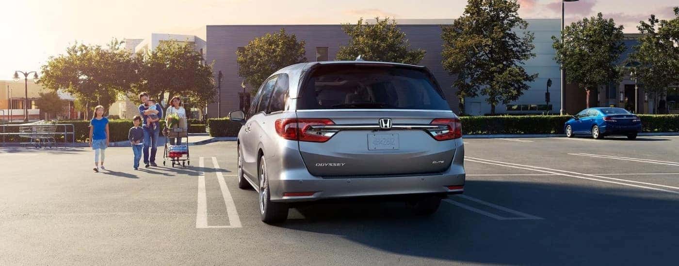 A silver 2024 Honda Odyssey Elite is shown near a store.