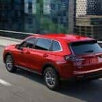 A red 2023 Honda CR-V EX is shown driving on a city street to a used Honda dealer in Oklahoma City.