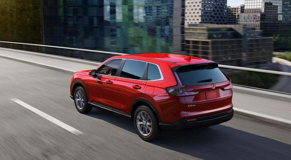 A red 2023 Honda CR-V EX is shown driving on a city street to a used Honda dealer in Oklahoma City.