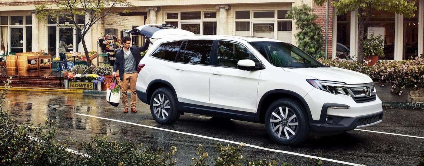 A white 2022 Honda Pilot EX-L is shown being loaded with groceries.