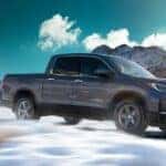A silver 2021 Honda Ridgeline RTL-E is shown driving through snow after visiting a Honda dealer near Tuttle, OK.