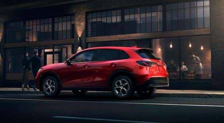A red 2024 Honda HR-V EX-L is shown from the side parked on the side of a city street.