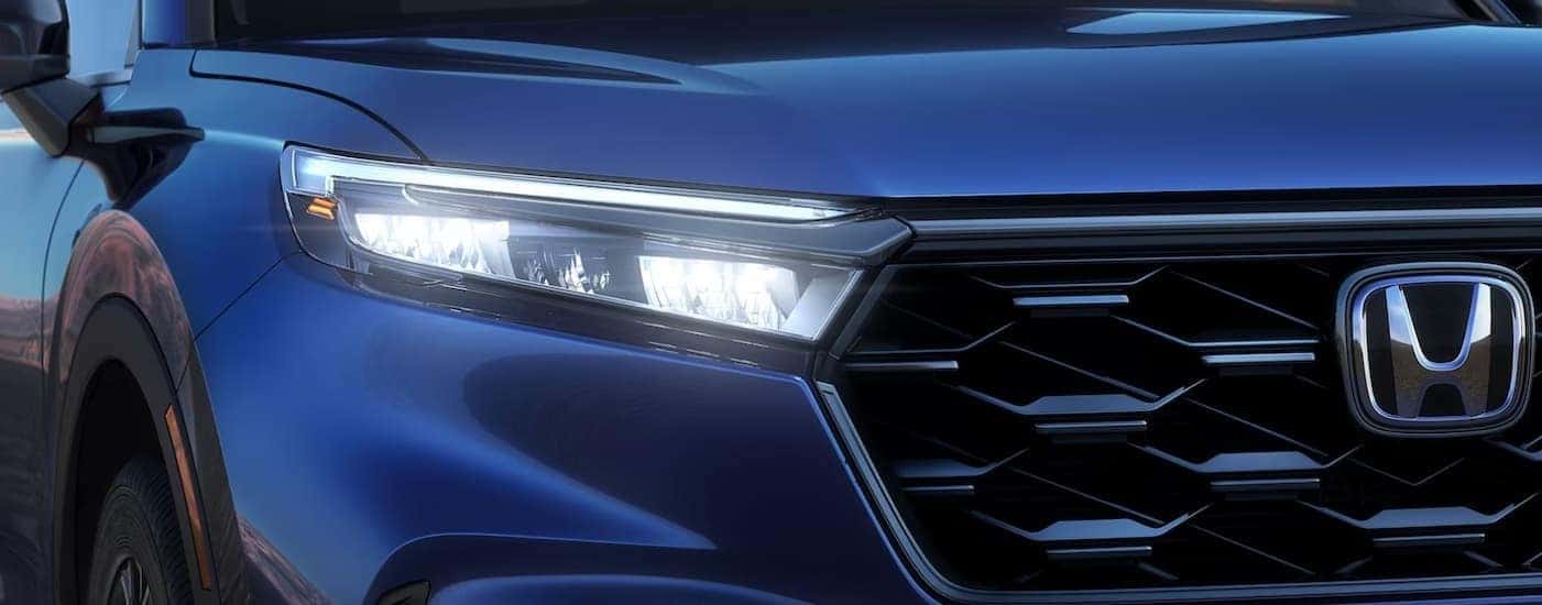 A close-up of a grille on a blue 2024 Honda CR-V is shown.
