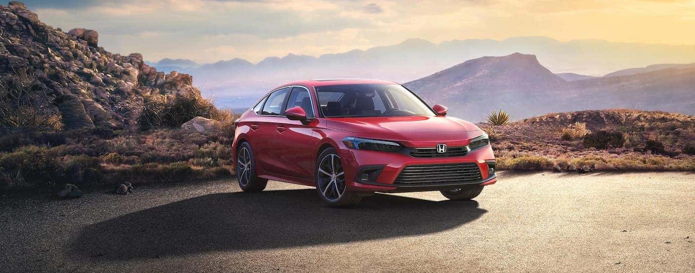 A red 2023 Honda Civic Touring is shown parked with a mountain view.