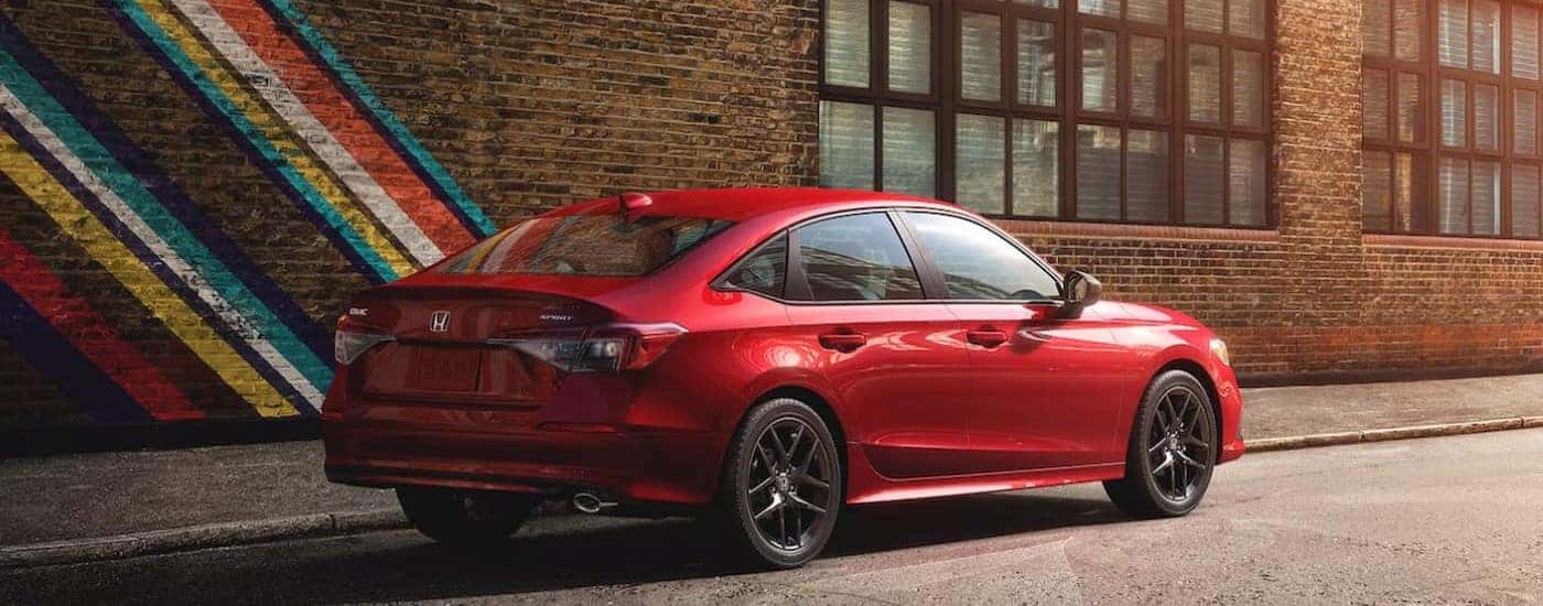 A red 2024 Honda Civic Sport is shown parked outside a building.